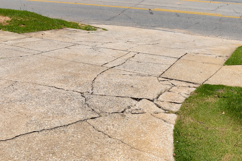 Cracked and broken concrete driveway showing visible signs of damage and wear near the street.
