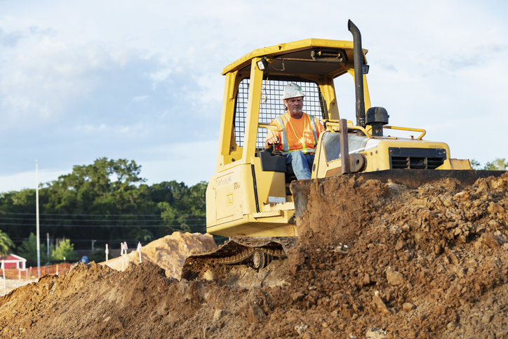 Man grading construction site with heavy machinery as part of professional site grading services