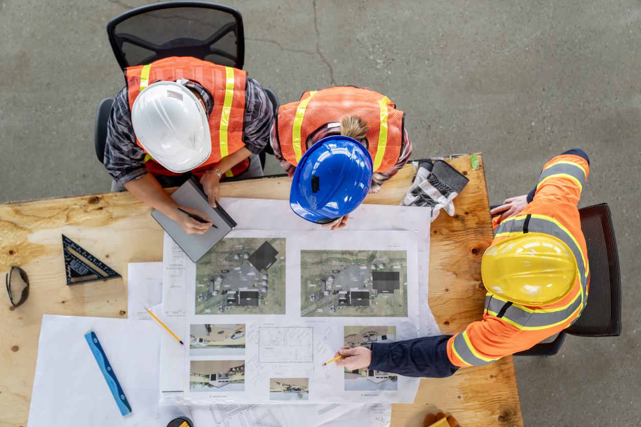 Oonstruction team in hard hats reviewing design and build plans for a Middle Tennessee construction project